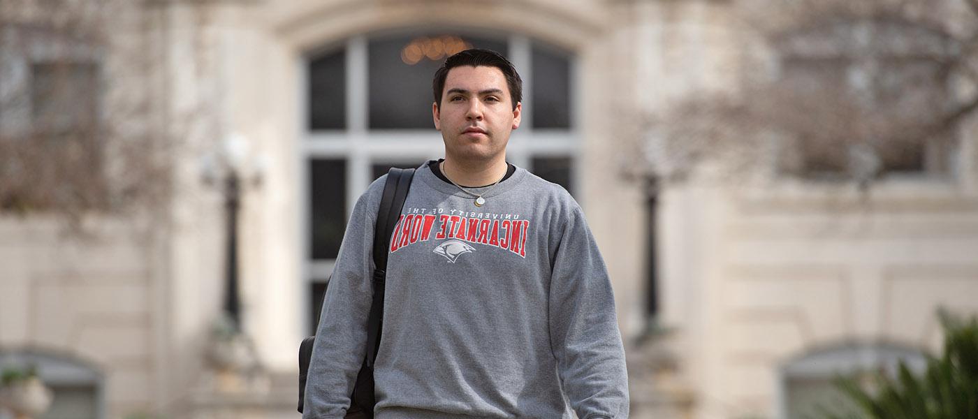 Student walking on campus with administration building in the background